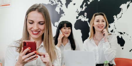 Travel agency working on-line in office, communicating with clients via phone and Internet over the world map. Manager gives information online, consulting touristsの写真素材