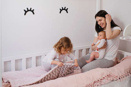 Mother with two kids in the kids play room spending time. Playing Together at Home with children, making bedの写真素材