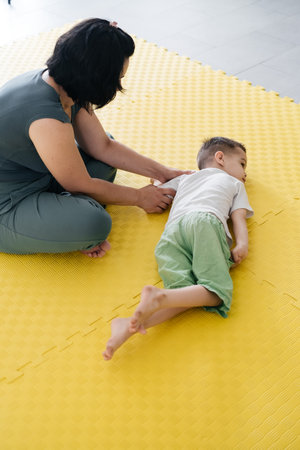 Rehabilitation of child with cerebral palsy in special center. Mother doing physical exercises and happily playing with boy, Sport activities for disabled kid. Inclusion and mobility Real people lifeの写真素材