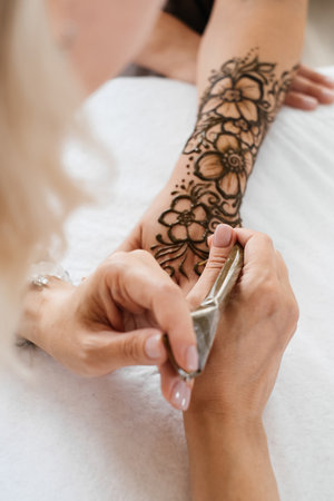 Top view art henna tattoo on woman hands. master artist drawing Arabic mehndi for bride before wedding. Close-up, overhead view. Floral design. Coneの写真素材
