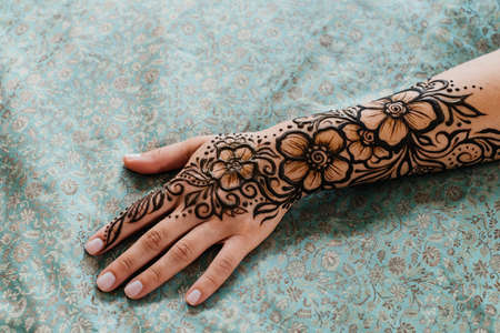Top view art henna tattoo on woman hands. master artist drawing Arabic mehndi for bride before wedding. Close-up, overhead view. Floral design. Coneの写真素材