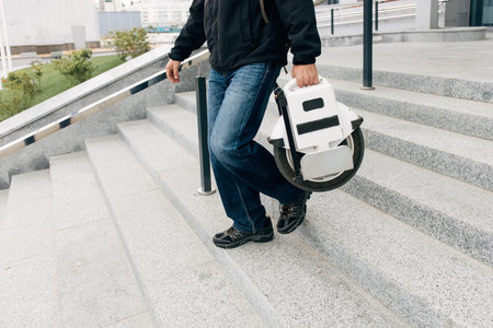 Man carrying electric unicycle on city street. Mobile portable individual transportation vehicle....