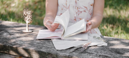 Woman writing, reading diary on the wooden table. Romantic memories. Hands flipping through...