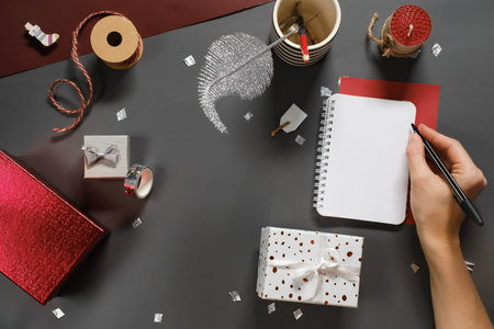 Opened empty note book for New Year wishes and resolutions on dark grey desk with small gift boxes....