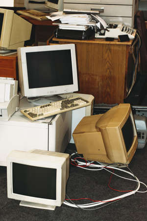Old computers, printers, typewriters, keyboards ready to trash from office. Retro device, screens and monitors on table and floorの写真素材