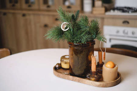 Christmas table decor on the kitchen table in eco style, rustic holiday serving with candles and pine tree brunch. Copy space. Beautiful handmade table settingの写真素材