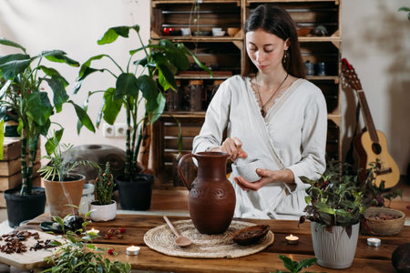 Pouring water into jug with cacao. Preparing ceremonial cocoa in atmospheric boho style cafe full of...