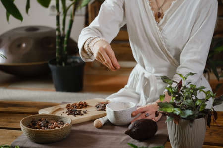 Cacao ceremony in atmospheric space with green plants and candles. Woman making ritual healthy drink from cocoa beansの写真素材