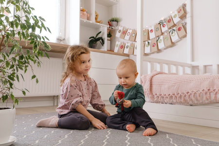 Sister and brother playing in the room before Christmas near advent calendar. Siblings in kids room on the floorの写真素材