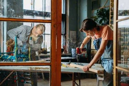 Man and woman working in workshop, doing furniture, reuse old materials to new product. awareness in consumption. Small family business. Recycling, sustainability refurbishments maintenance for homeの写真素材