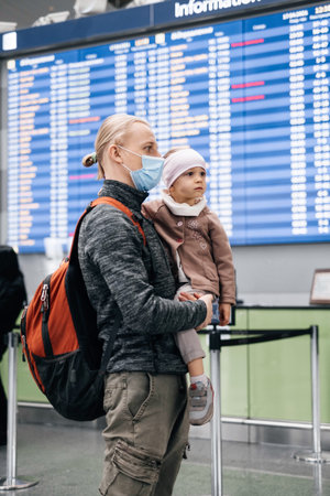 Man and girl watching timetable information at the airport, passengers waiting for a plane. Family...