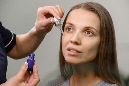 Application oil serum from pipette. Natural organic cosmetic product for facial skincare and skin regeneration around eyes zone. extreme close up. Anti aging therapy in clinikの写真素材