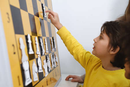 Child Thinking Hard On Chess Combinations on the wall on tournament for kids Intellectual game, hobby for childrenの写真素材