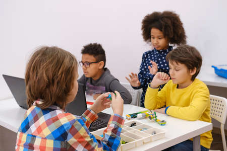 Kids learning coding, science and technology at school class. African American and Caucasian children studding with laptop computers on STEM lesson. Diversity in modern innovative educationの写真素材
