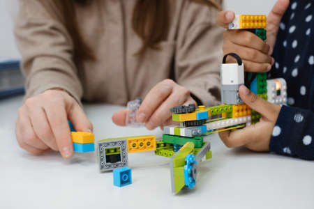 Coding Class, school girl constructing robot arm mechanism. multiethnic children making science, technology tasks with tablet. Modern education African American girl having fun experimenting on lessonの写真素材