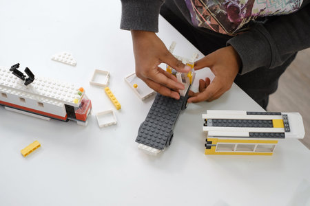 Kid constructing transport on STEM lessons. Close-up of child African American hands with building...