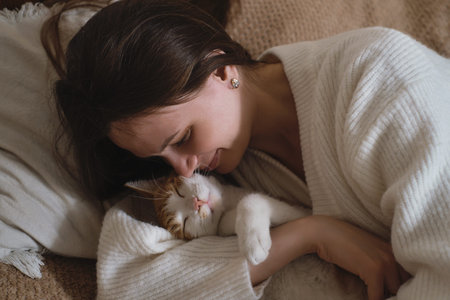young woman holding cute ginger cat with green eyes. Female hugging her cute short hair kitty in...