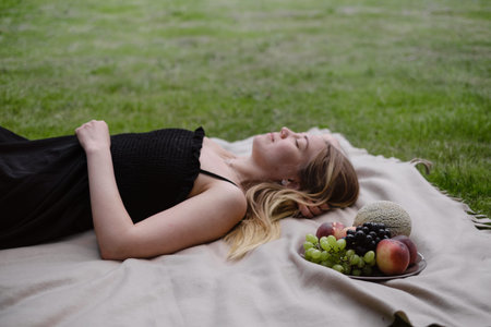 Woman on picnic in green garden On blanket. Cheerfully female spend time outdoors, eating summer...