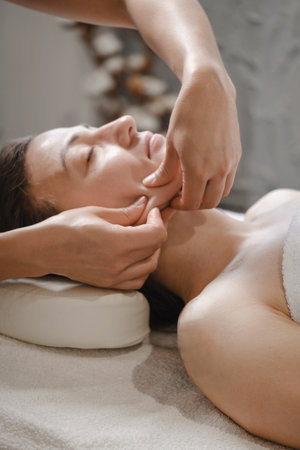 face massage with oil in traditional style made by professional beauty therapist women. anti-age...