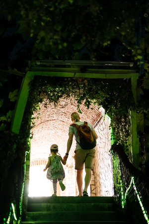 Father and child walking though the tunnel. People going away to the light view from the back Family walk to the zoo or castle. Discover togetherの写真素材