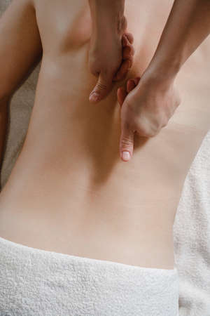 woman having back massage treatment in therapy clinic. Oil back massage, Spa and healthcare concept. Pain relief. Close-up, top view with copy space. Hands on human back, spineの写真素材