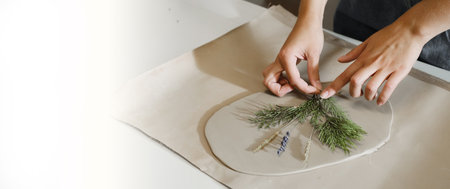 Banner Clay handmade Ceramic plates rolled on the table with plants and flowers. Top view on handcrafted pottery, close-upの写真素材