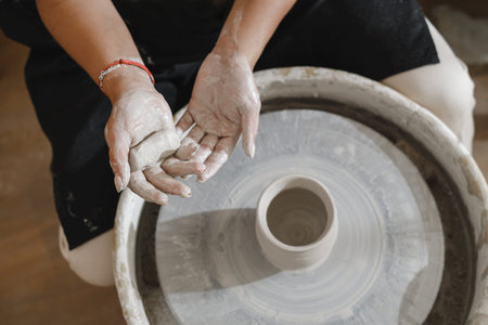 Potter hands over wheel. self-employed pottery artist in creative studio modeling from raw clay...