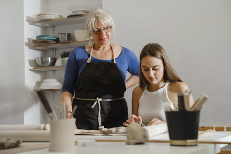 Pottery workshop in studio. People working with clay on the table. Adults learning to do ceramic...