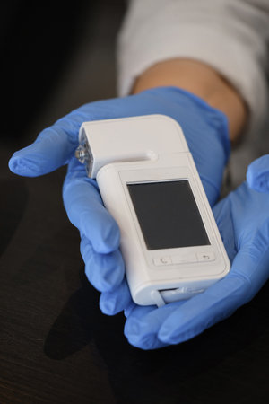 Hands holding special dermatology equipment system, hair loss and trichology concept. Analyzing Hair With Analysis System Digital Trichoscope. Close-upの写真素材