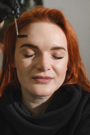 Eyebrows makeup. Face closeup of beautiful woman having brows correction in beauty salon. Beautician...