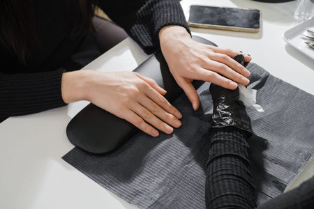 Nail service. Cropped view of the girl getting nails done at beauty salon. Manicure master doing...