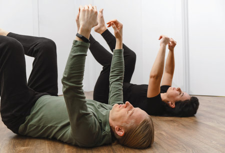 Rehabilitation exercise. Physical therapy concept. Two people laying on the back on the floor with...