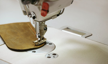 Sewing eco leather item. Closeup of the sewing machine and piece of eco leather. Sewing machine, tailoring, small business concept. Craftsman workshop. Copy spaceの写真素材