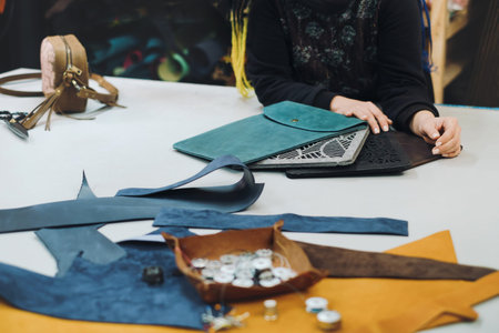 Eco leather laptop cases production. Close up of female tailor working with eco leather textile at...