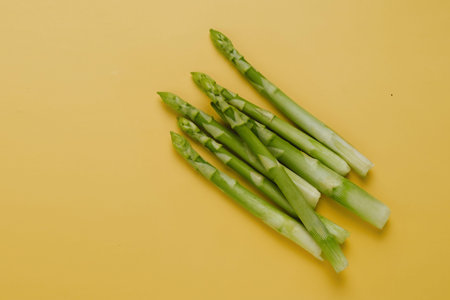 Fresh green asparagus on yellow background, minimalistic, top view. copy space. Healthy food for...