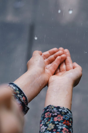 kids hands catching raindrops, weather concept. Closeup of rain falling in hands