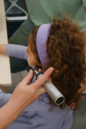 Child hearing test. Doctor audiologist examineing kids ear and assess disorder of hearing using...