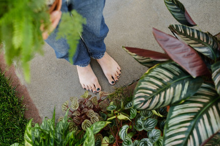 Woman holding houseplant on head over yellow wall. Relaxation concept. Confident florist, owner of small business flower shop Holding potted fern in workplace. Looking up. Enjoying jobの写真素材