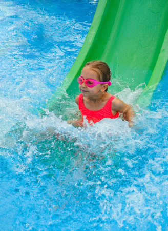Happy child in outdoor swimming pool. Preschool girl enjoying summer time swimming. Kid having fun...