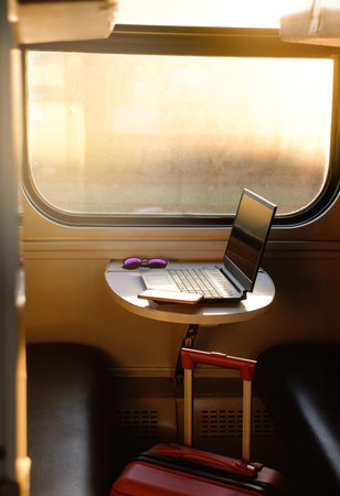 Working in train on sunset. Laptop standing on the table by the window. Nobody. Laptop computer while traveling with high-speed train. Modern and fast travel conceptの写真素材