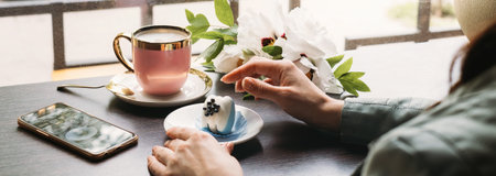 Blue macaroon dessert, original and stylish dessert in cafe in front of window, Hand holding plate with tasty sweet. bannerの写真素材