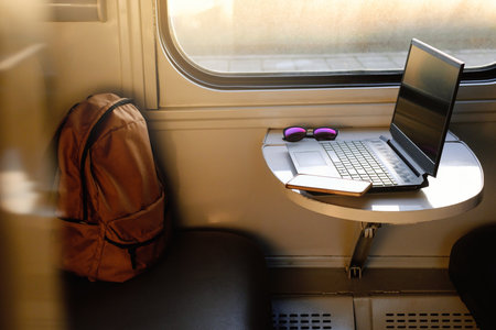 Working in train on sunset. Laptop standing on the table by the window. Nobody. Laptop computer while traveling with high-speed train. Modern and fast travel conceptの写真素材