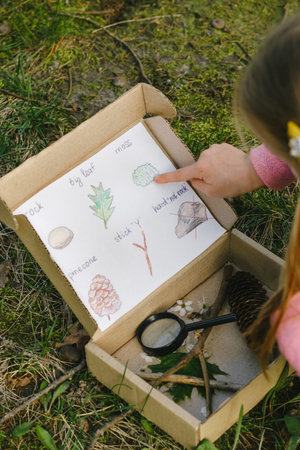 Scavenger hunt for kid in the park. Girl learning about environment. Natural education activity for...