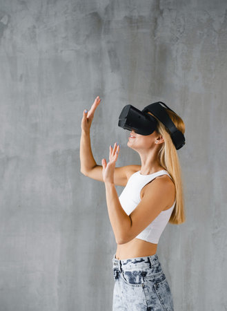 Female explores virtual reality over grey wall. Side view, touching cyber world. Copy space