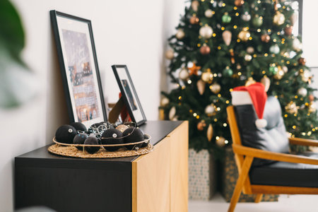 Cozy Armchair near Christmas tree in sunny room with big windows. Santas hat in the morning. Nobody....