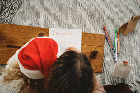 Mother with toddler girl writing Christmas letter and doing advent calendar tasks in bedroom. Festive activities for children at home. Happy dreaming girl creating craftの写真素材