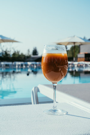 Relax by the beautiful pool during your stay at a modern hotel. Sip on a vibrant drink while enjoying the serene atmosphere in a lush travel destination.の写真素材