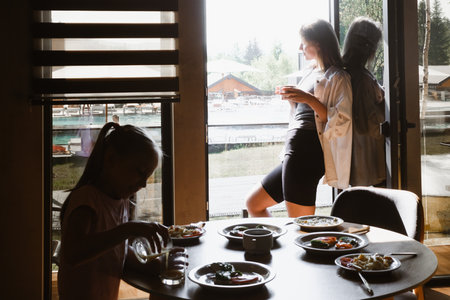 Mother and daughter having meal together in a stylish, contemporary space. Family eating delicious breakfast.の写真素材