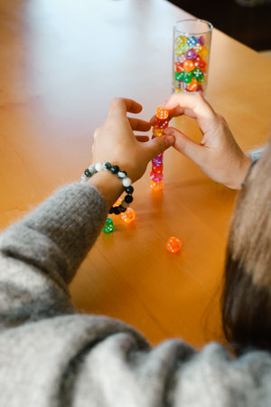 Person stacks colorful dice while playing a table game. Hands with dice , closeup. Trying luck and practicing concentration and calming downの写真素材