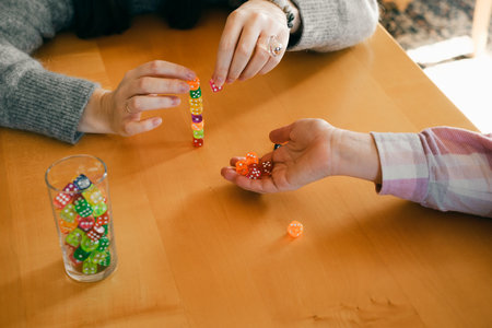 Person stacks colorful dice while playing a table game. Hands with dice , closeup. Trying luck and practicing concentration and calming downの写真素材